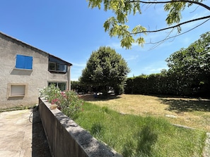 Ein zweistöckiges Haus mit einer Stein-Fassade, einem blauen Fensterladen und einem Rasen mit einer Hecke.