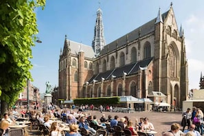 A historic building with a prominent clock tower, large arched windows, and a central courtyard with outdoor seating. - Family vacation apartment North Sea, nature, fitness & wellness -max 2 adults + 2 children- (Aerdenhout)