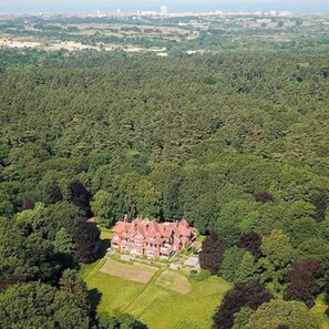 An aerial view of a large, red-roofed estate surrounded by dense greenery, with a clear view of the property layout and surrounding landscape. - Family vacation apartment North Sea, nature, fitness & wellness -max 2 adults + 2 children- (Aerdenhout)