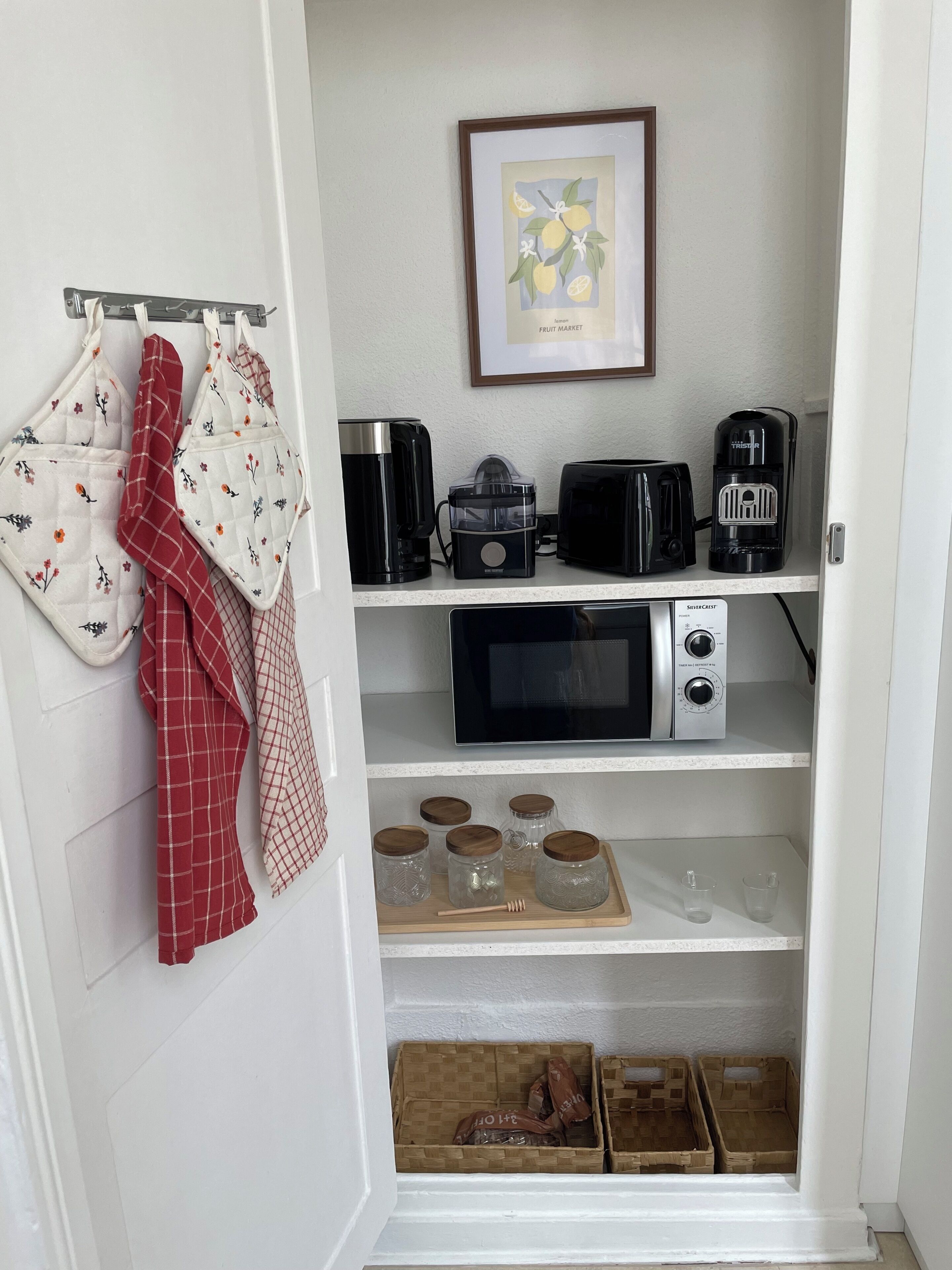 A kitchen with a microwave, toaster, coffee maker, and jars on shelves.