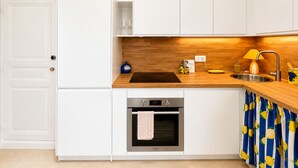 Eine Küche mit weißen Schränken, einer Holz Arbeitsplatte, einem eingebauten Backofen und einem Spülbecken.