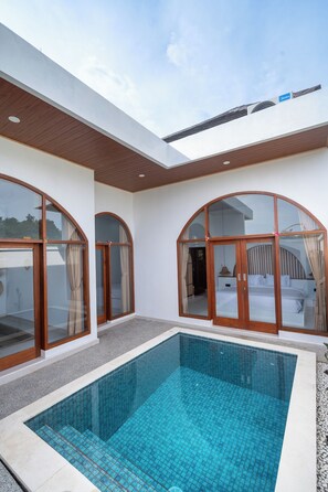 A modern pool area with glass doors and a clear blue pool.