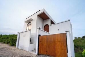 A modern house with a white exterior, a wooden door, and a small window.