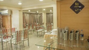 A dining area with tables and chairs, a 'No Smoking' sign, and a water dispenser. - HOTEL ORCHARD (Pune)