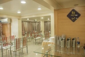 A dining area with tables and chairs, a 'No Smoking' sign, and a water dispenser. - HOTEL ORCHARD (Pune)