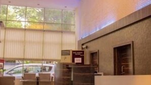 A reception area with a chandelier, a reception desk, and a seating area with chairs. - HOTEL ORCHARD (Pune)