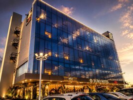 Un moderno edificio de hotel con fachada de vidrio, que muestra el rótulo 'Euro Hotel', cuenta con una entrada destacada y un aparcamiento visible.