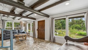 A room with stone flooring, a wooden bench, a sofa, and a dining table. - 3BR log cabin west OKC, Sleeps 10 — fenced yard, grill, patio, full kitchen. (Oklahoma City)