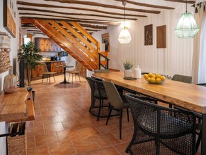 A wooden dining table with chairs, a staircase, and a kitchen area. - Vrbo Property (La Gila,Alcalá del Júcar)