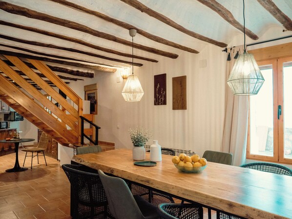 A dining area with a wooden table, chairs, hanging lights, and a staircase. - Vrbo Property (La Gila,Alcalá del Júcar)