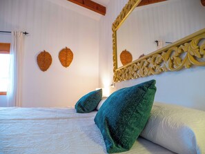 A bedroom with two beds, a large ornate mirror, and decorative wall art. - Vrbo Property (La Gila,Alcalá del Júcar)