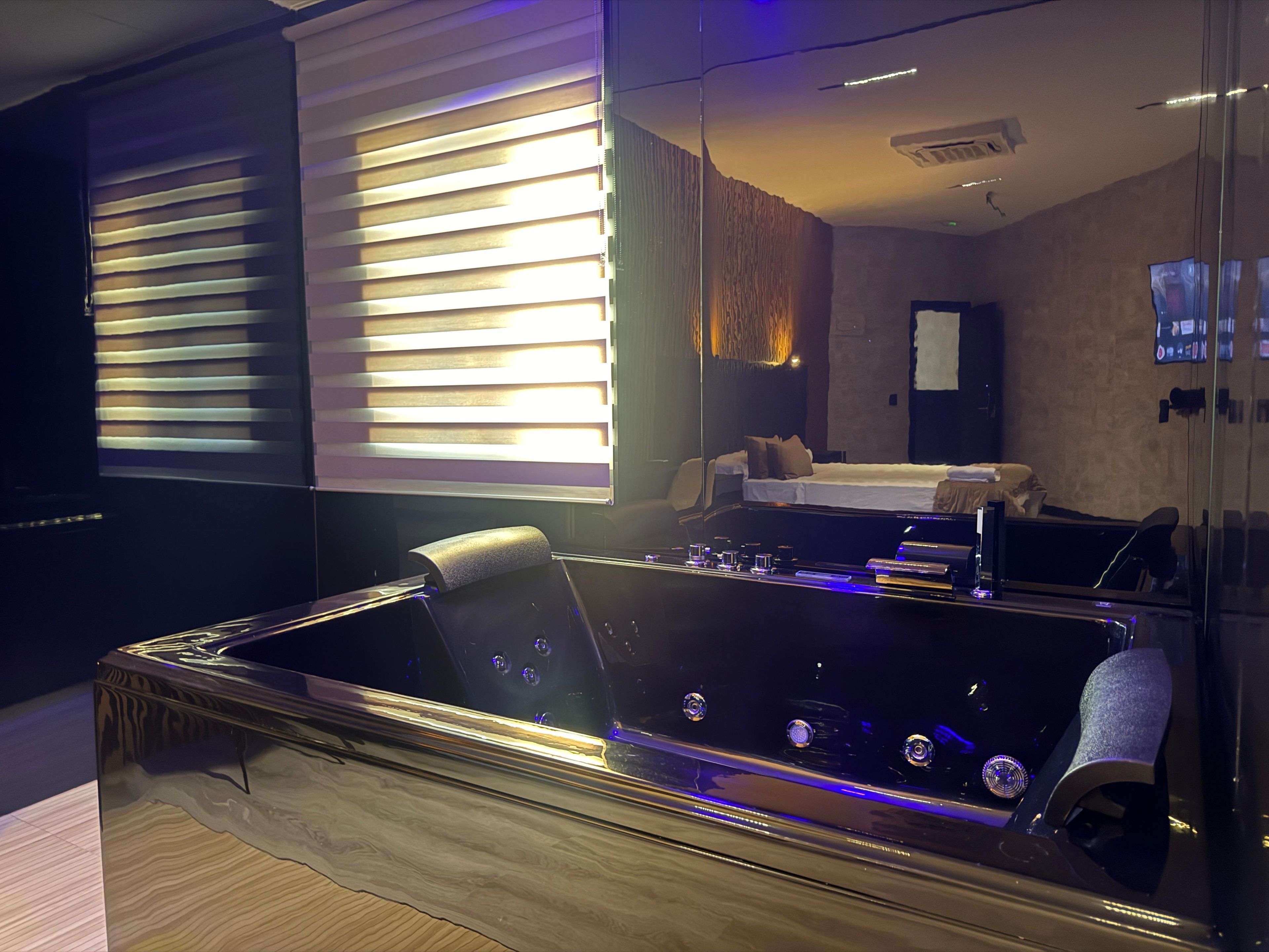 Une chambre moderne avec une grande baignoire, un lit et un téléviseur fixé au mur.