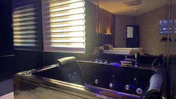 Une chambre moderne avec une grande baignoire, un lit et un téléviseur fixé au mur.