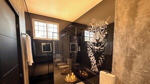 Un baño moderno con ducha envuelta en vidrio, un espejo grande y un mural de leopardo en la pared.