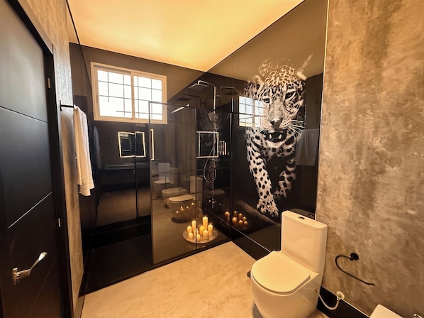 Un baño moderno con ducha envuelta en vidrio, un espejo grande y un mural de leopardo en la pared.