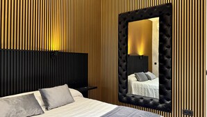 Un dormitorio moderno con una cama grande, cabecera, espejo y pared con listones de madera verticales.