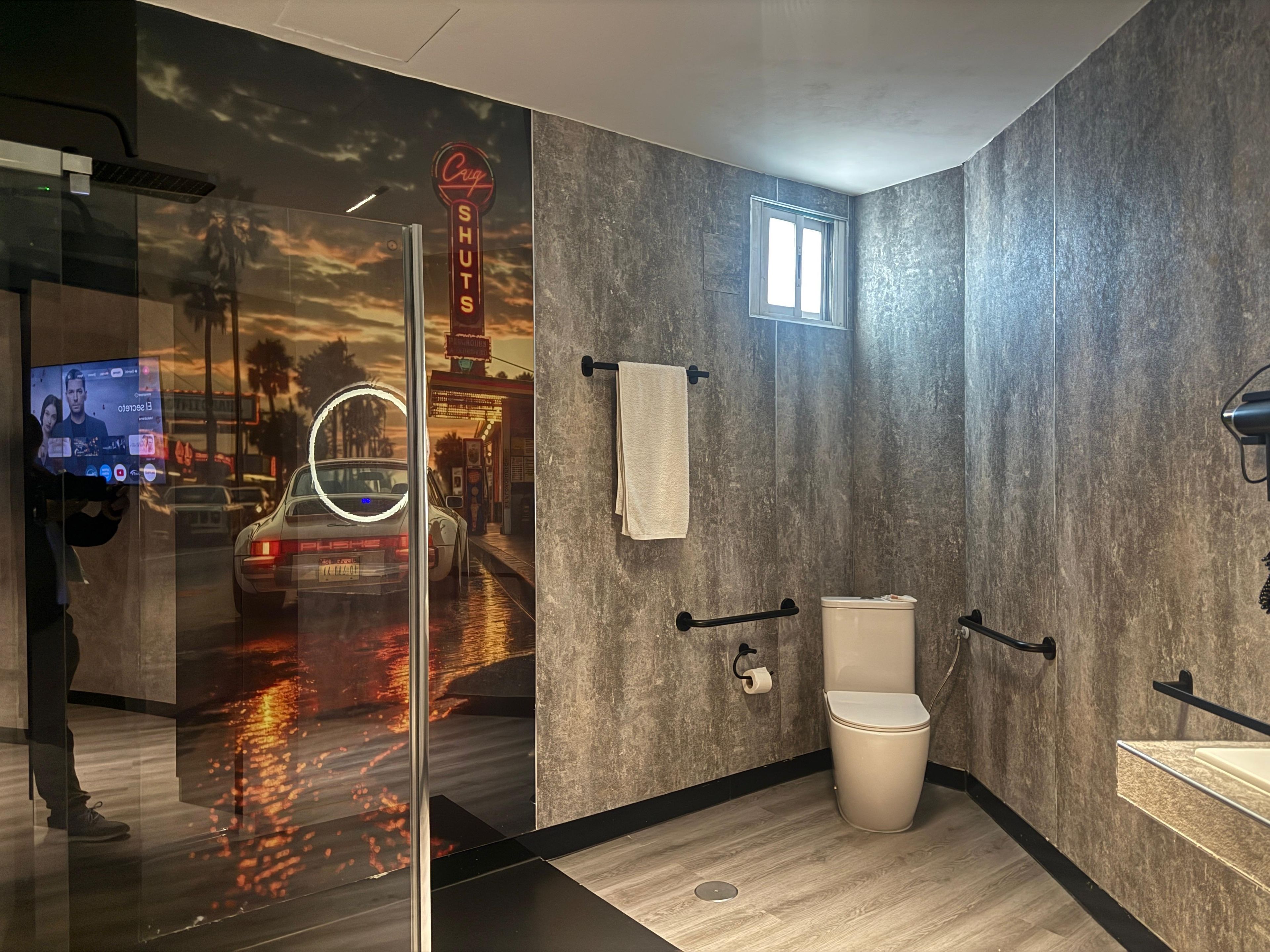 A modern bathroom with a glass shower enclosure, a toilet, and a sink.