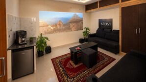 A modern living room with a sofa, coffee machine, and a TV. - Aviora Residencies Gachibowli  (Hyderabad)