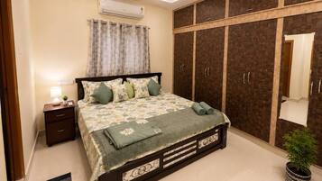 A bedroom with a bed, nightstand, wardrobe, and a ceiling fan.