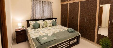 A bedroom with a bed, nightstand, wardrobe, and a ceiling fan.
