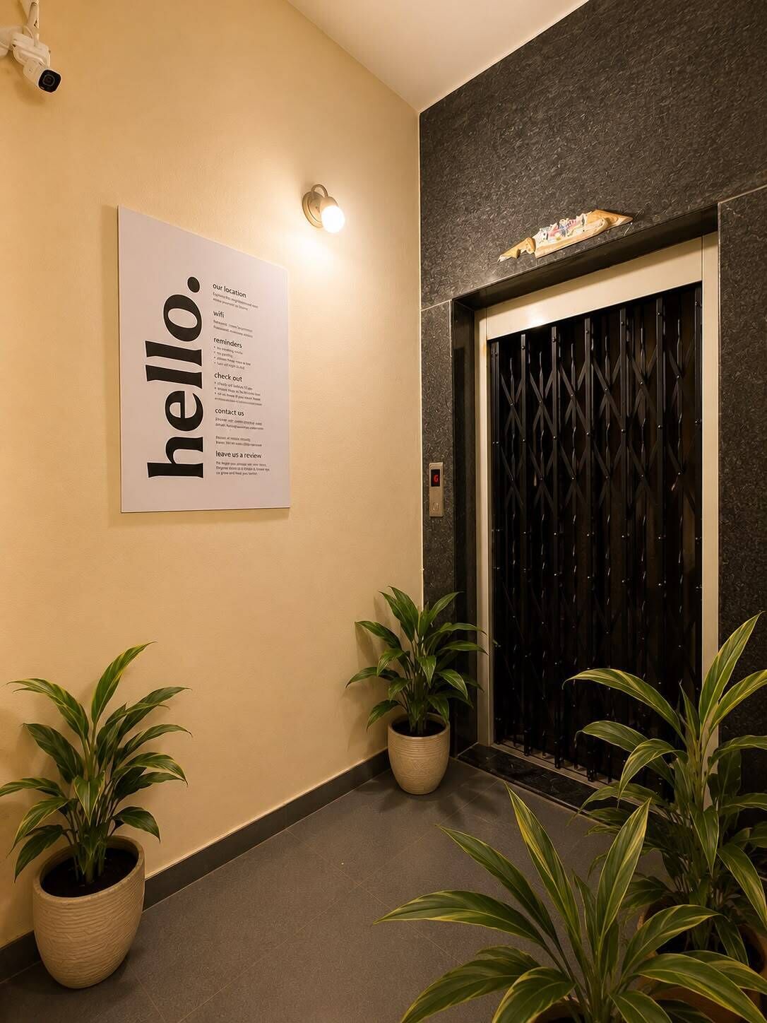 A hallway with a 'hello.' sign, potted plants, and an elevator.