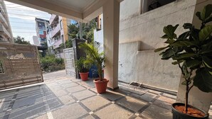 A tiled patio area with potted plants, a metal gate, and a concrete wall. - Aviora Residencies Gachibowli  (Hyderabad)