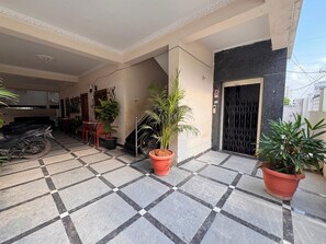 A tiled patio with potted plants, a motorcycle, and a dining area with chairs and a table. - Aviora Residencies Gachibowli  (Hyderabad)