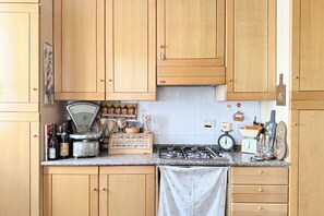 Una cocina con armarios de madera, una estufa a gas, una balanza y diversos utensilios de cocina sobre la encimera.
