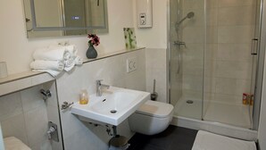 Un bagno moderno con box doccia in vetro, lavandino bianco e water.