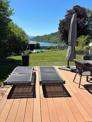 A deck with two lounge chairs, a wicker table, and an umbrella. - Golden Rooms Exclusive (Völkermarkt)