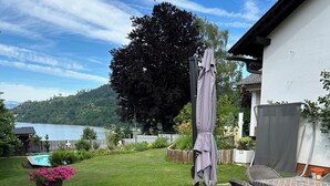 A deck with outdoor furniture, a pool, and a view of a lake and hills. - Golden Rooms Exclusive Wing for 2 Adults and 1 Child (Völkermarkt)