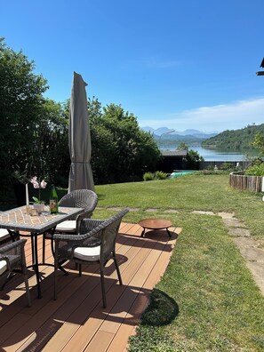 Un patio con mobiliario de mimbre, una mesa y una sombrilla.