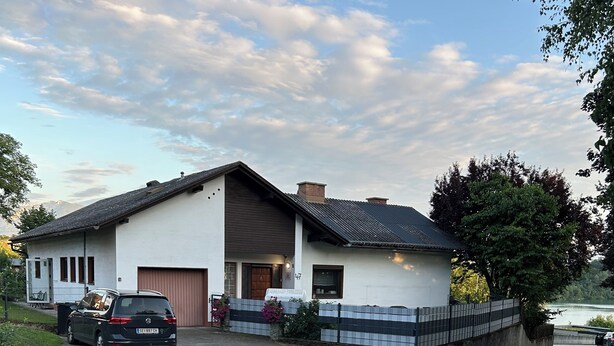 A two-story house with a garage, a driveway, and a tree in the background. - Golden Rooms Exclusive Wing for 2 Adults and 1 Child (Völkermarkt)