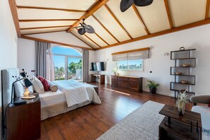 A spacious bedroom with a large bed, a TV, a wooden floor, and a balcony with a view. - Luxury 5BR Villa Benalmádena | Pool & Jacuzzi REF073 (Benalmádena)