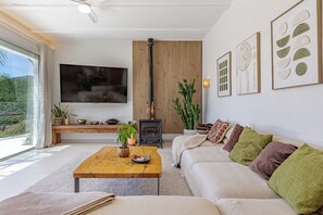 A living room with a sofa, coffee table, TV, wooden panel wall, and a fireplace.