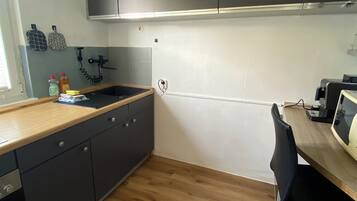 A kitchen with dark cabinets, a wooden countertop, a sink, and a chair.