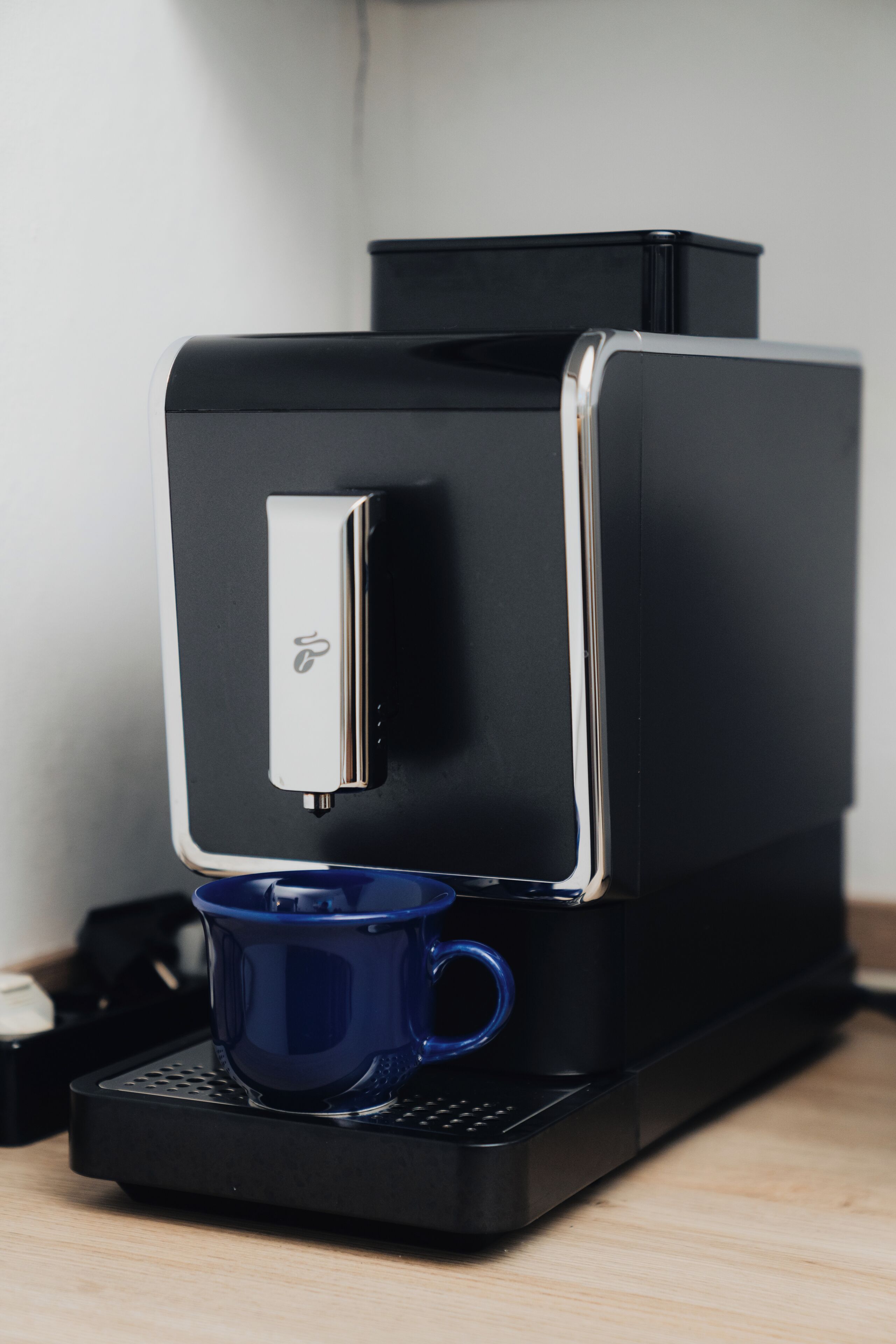 A coffee machine with a blue cup holder and a silver logo.