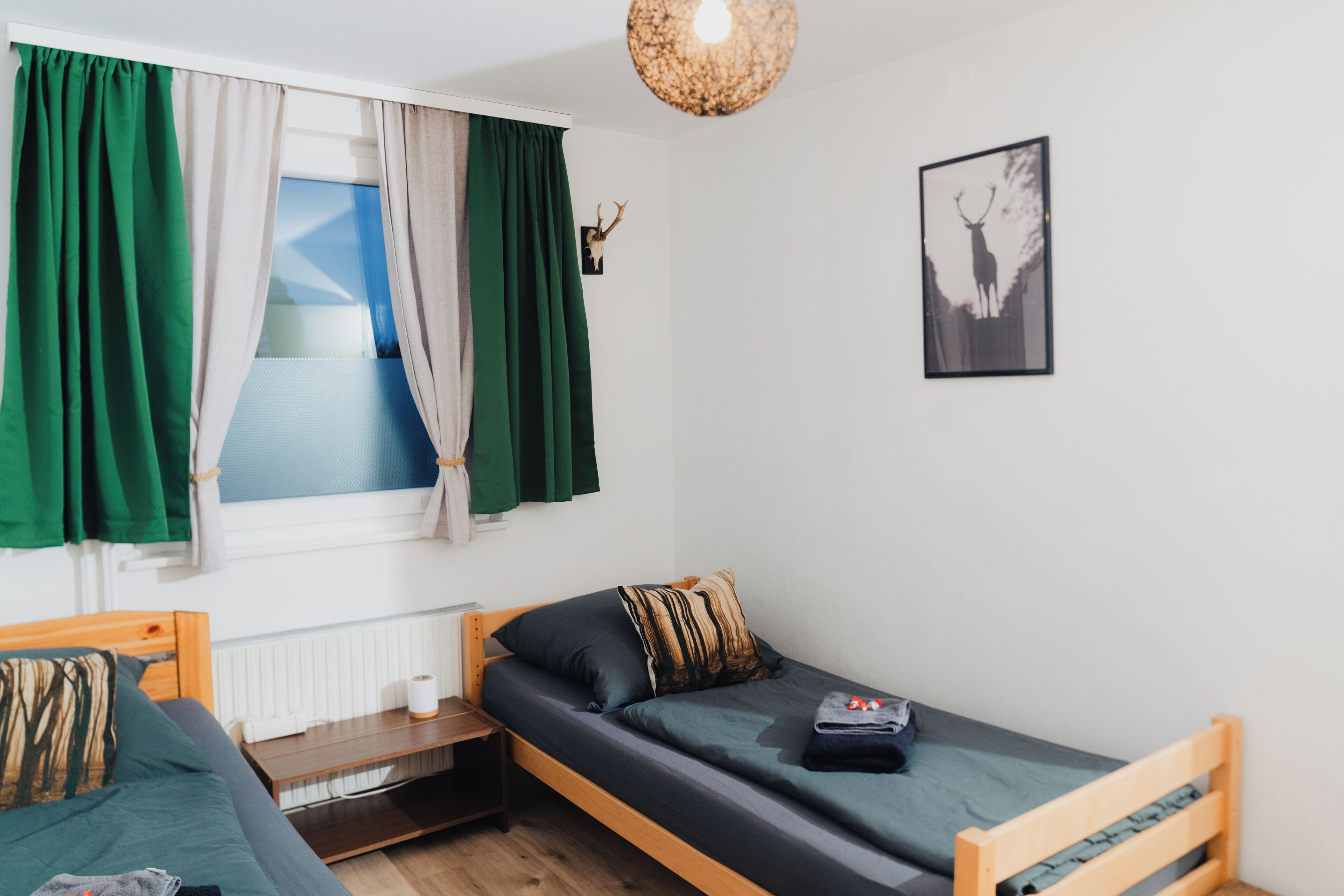 A small, single-bed room with a window, a picture on the wall, and a wooden headboard.