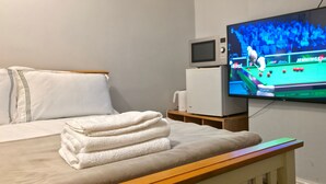 Ein Hotelzimmer mit einem Bett, einem Fernseher, der eine Snooker-Übertragung zeigt, einer Mikrowelle und einem kleinen Tisch.
