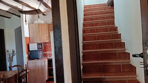 Un escalier menant à un palier, avec un coin cuisine visible au fond.