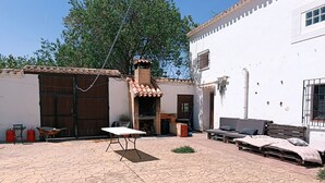 Une cour avec un sol carrelé, une table, un banc et un petit espace aménagé en jardin.