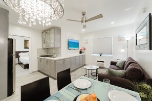 A modern kitchen with a dining area, a ceiling fan, and a TV. - South Beach Ocean Drive Villa | Pool | Oceanfront (Miami)
