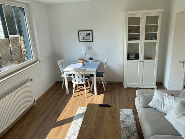 A dining area with a table, chairs, a cabinet, and a window.
