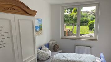 Ein Schlafzimmer mit Bett, einem Fenster mit Gartenblick, einem weißen Kleiderschrank und einem Bild an der Wand.