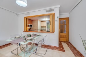 A dining area with a glass table, chairs, and a wooden door in the background. - LXR Coloso, 2-bedroom apartment with an ocean view. (Benalmádena)