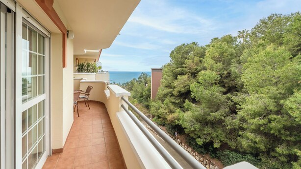 A balcony with a view of the sea and trees. - LXR Coloso, 2-bedroom apartment with an ocean view. (Benalmádena)