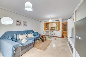 A living room with a sofa, coffee table, and dining area with chairs and a table. - LXR Coloso, 2-bedroom apartment with an ocean view. (Benalmádena)