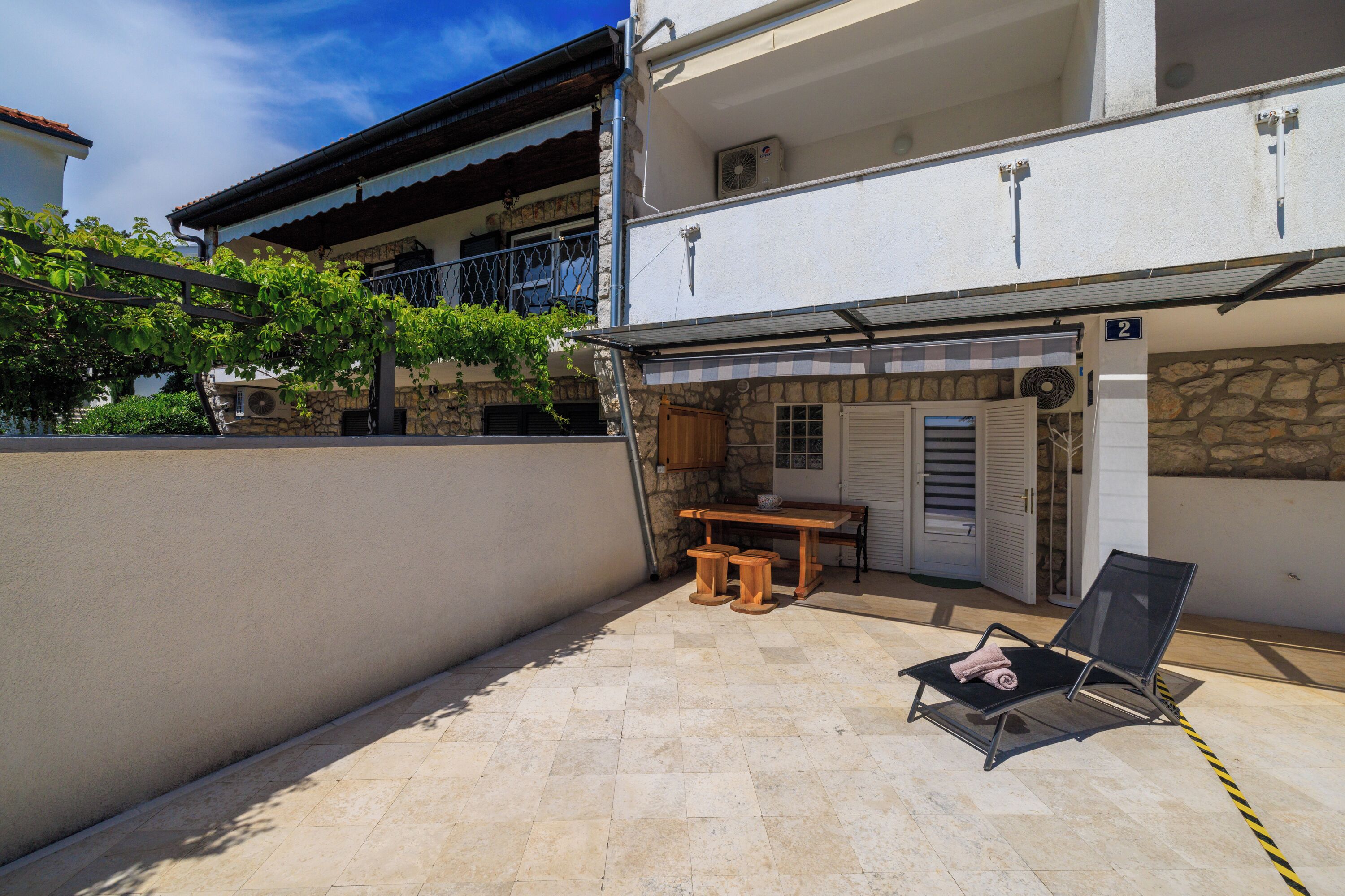 Ein zweistöckiges Gebäude mit Balkon, Tisch und Stuhl vor der Fassade.