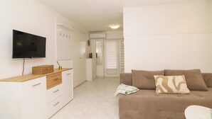 Ein Wohnzimmer mit einer Couch, einem Fernseher und einem kleinen Tisch.