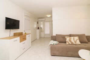 Ein Wohnzimmer mit einer Couch, einem Fernseher und einem kleinen Tisch.